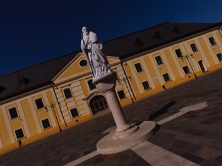 Stone statue on a column in front of a yellow historic building